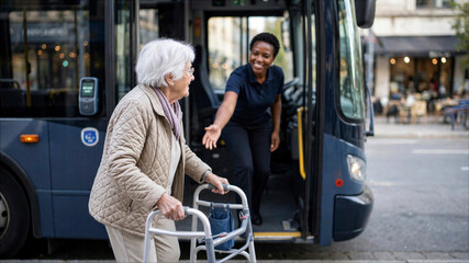 Obraz premium Friendly bus driver helping an elderly woman with a walker to board public transportation