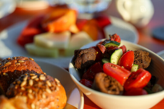 Assorted pastries, breadsticks, salad, and fruit served for breakfast at a sunlit caf&eacute; in Athens, Greece.