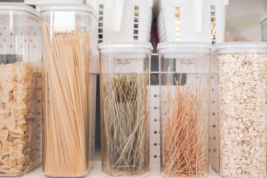 Pantry, organization, kitchen, storage, pasta, spaghetti, oats in transparent airtight containers with elegant labels on a shelf, showcasing a tidy and minimalist home kitchen decor.