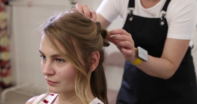 Hairdresser styling woman's hair in beauty salon, closeup