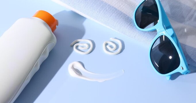 Woman applying sun protection product, smiling face made with sunscreen and beach accessories on light blue background, closeup