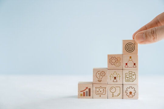 Hands holding wooden blocks with business icons, business strategy management, set goal and target, collaboration business concept
