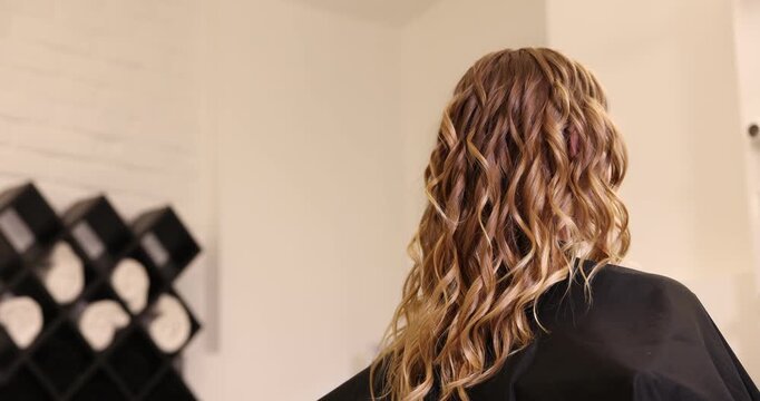 Hairdresser styling woman's hair in beauty salon, closeup