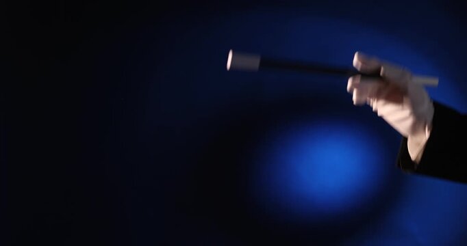 Magician with wand on dark blue background, closeup
