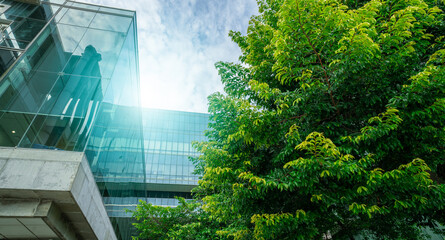 Naklejka premium Sustainable green building. Eco-friendly building. Sustainable glass office building with trees for reducing carbon dioxide. Green company office with green environment. Corporate building reduce CO2.