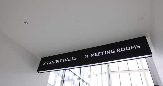 A straightforward B-roll shot featuring a clearly marked "Exhibit Halls" directional sign, providing wayfinding and navigation for attendees moving through a large convention center or event venue.