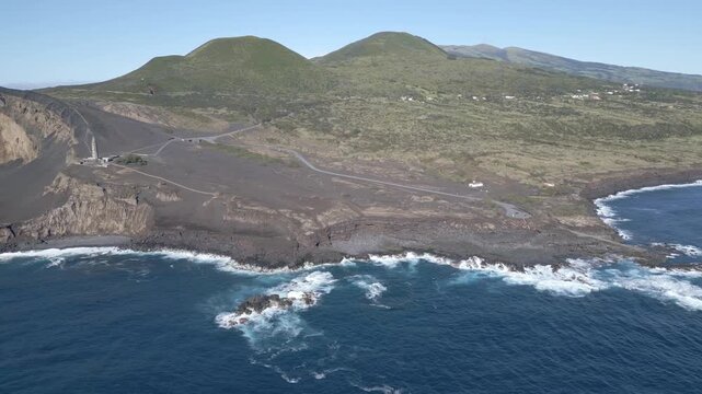 Aerial view of rugged volcanic coastline with waves crashing against dark cliffs