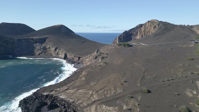 Capelinhos Lighthouse on Faial Island, Azores, Portugal, surrounded by volcanic terrain, rugged Atlantic waves created by the 1957&ndash;58 eruption, slow motion wide aerial view