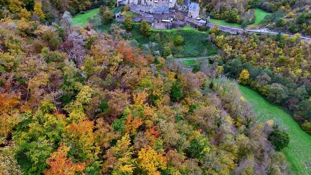 Top-down drone footage rises above colorful autumn forest before revealing the medieval Eltz Castle nestled in the scenic Elzbach valley. Location: Wierschem, Germany