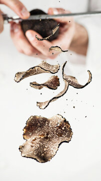 Black truffle being sliced with a grater, showcasing flying shavings in motion