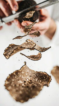 Black truffle being sliced with a grater, showcasing flying shavings in motion