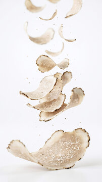 Slices of white truffle (Tuber magnatum) falling from scissors in a clean environment