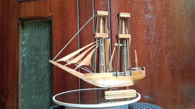 A miniature phinisi ship is displayed on a photographic recorder. This miniature is a replica of a traditional sailing vessel from the Bugis and Makassar tribes of South Sulawesi.