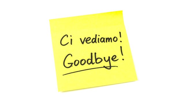 A yellow sticky note with "Ci vediamo! Goodbye!" handwritten in black marker, isolated on a white backdrop