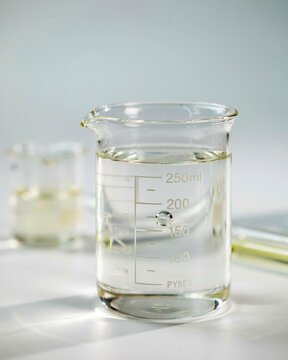 Beaker with clear liquid and a bubble on a light surface laboratory science