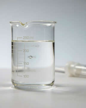 Close-up of a beaker with clear liquid and measurement markings laboratory science
