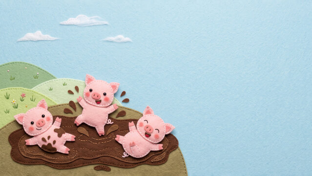 Handcrafted 3D cut felt illustration of three happy pigs splashing in a mud puddle on a green hill beneath a minimalist light blue sky.