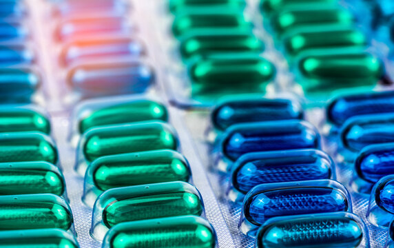 Closeup blue and green soft gel capsule pills in blister packaging for pharmaceutical manufacturing, healthcare industry, medicine production, pharmacy products and modern medical treatment concept.