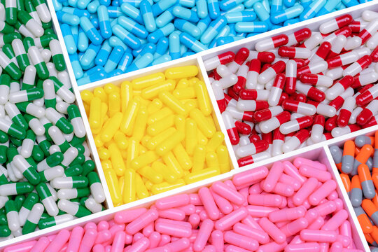 Above view capsule pills in plastic box. Multi colored capsule pills. Vitamin and supplement concept. Pharmaceutical industry. Pharmacy products. Healthcare and medicine. Pharmaceutical manufacturing.