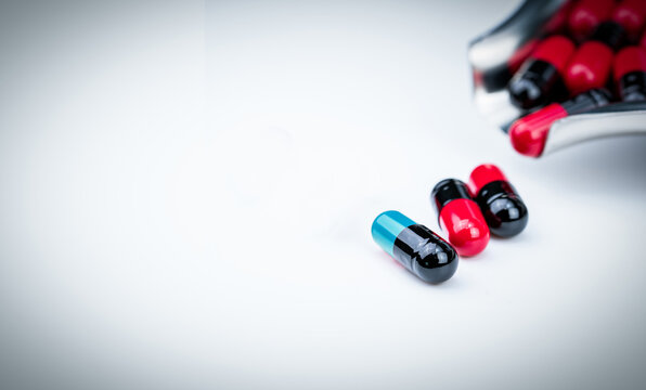 Selective focus blue-green capsule pill and drug tray with red-black capsule. Global healthcare. Antibiotics drug resistance. Antimicrobial capsule pills. Pharmacy background. Pharmaceutical industry.