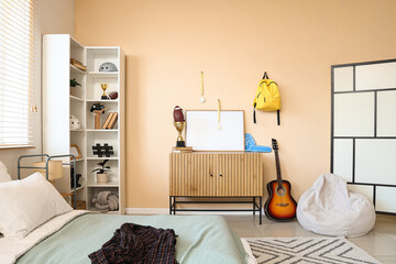Teenage boys bedroom interior with bed, bookshelf, guitar, and sports memorabilia, modern home decor © Pixel-Shot