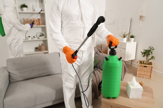 Male worker in hazmat suit disinfecting room