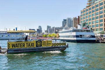 Obraz premium TORONTO, ONTARIO, CANADA - 30 MAY 2026: Toronto Embankment. Yellow Toronto Harbour Water Taxi and Northern Spirit cruise ship at the downtown waterfront on Lake Ontario