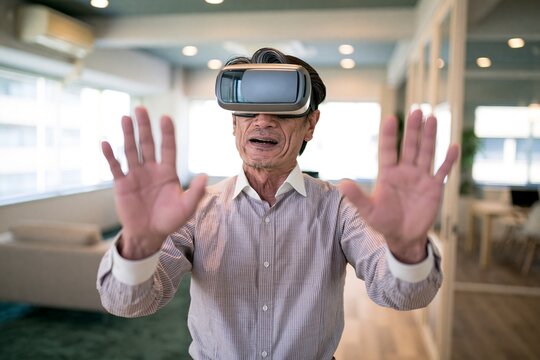 自宅でVRゴーグルを装着し手を伸ばしてバーチャル体験を楽しむシニア男性