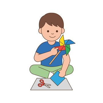 A young boy making a colorful paper pinwheel toy at home