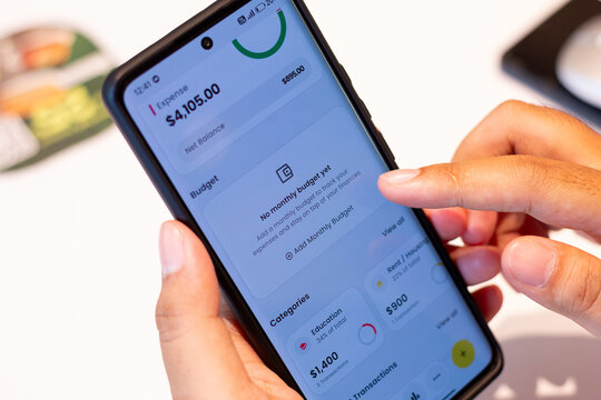 Person uses smartphone app for budget and expense tracking on a table