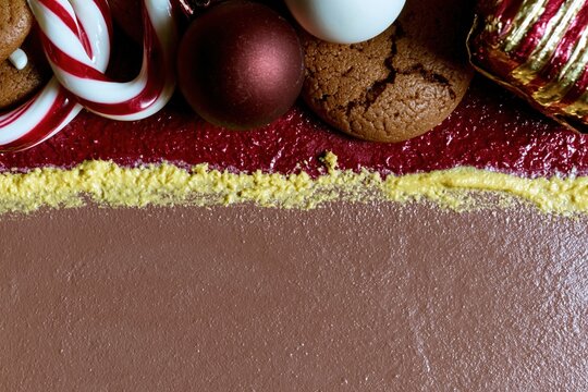Gingerbread cookies and candy canes with holiday ornaments on a textured red and taupe background for a seasonal Christmas greeting with copy space