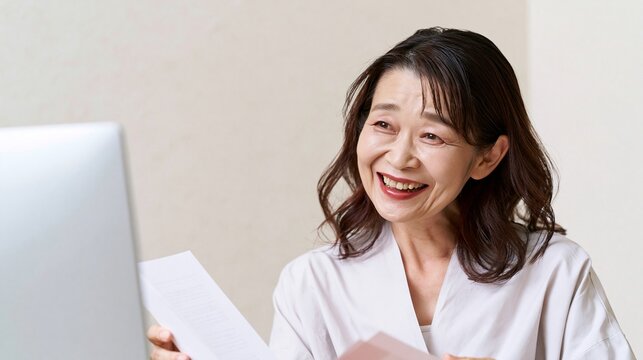 パソコンの画面を見ながら笑顔で書類を確認する女性