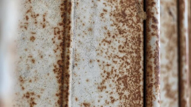 Slow motion macro video with shallow depth of field showcasing detailed rust particles, oxidized texture, and coarse metallic surface on an old door.
