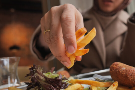 Woman reaching for fries at a cafe during lunch time