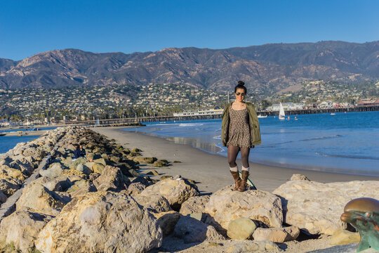 Woman stands on rocky jetty, smiling at camera