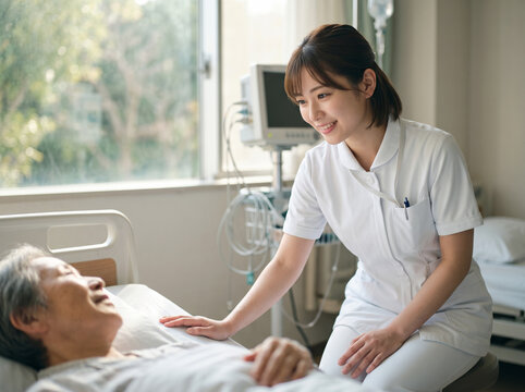 病床の高齢患者に笑顔で視線を合わせ心のケアを行うナースの女性