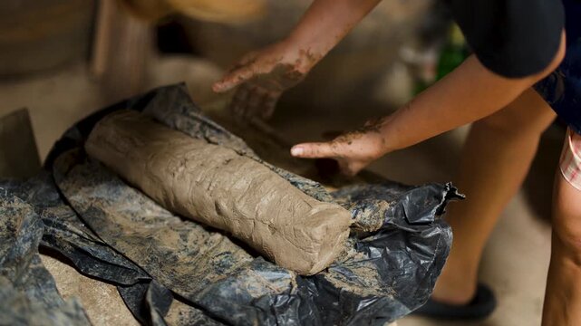 Artisan Hands Kneading Raw Clay in Traditional Thai Pottery Workshop