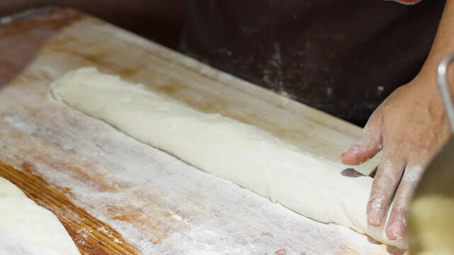 Asian Chef Brushing and Cutting Dough on Wooden Bench