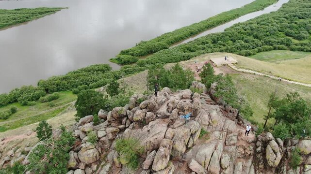 Aerial view of a man and woman standing on top of the rocky Sleeping Lion Mountain (Omulevaya), overlooking the Selenga River near Ulan-Ude in Buryatia, Russia.