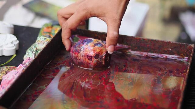 Hand dipping egg in colorful paint at art event
