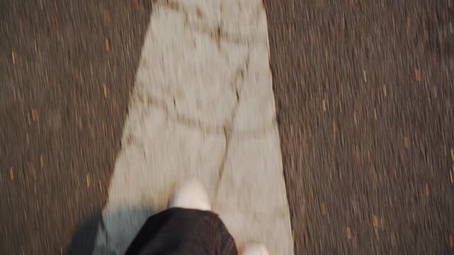 POV Close Up View of Feet Walking Forward Over Straight Arrow Marking on Asphalt Road