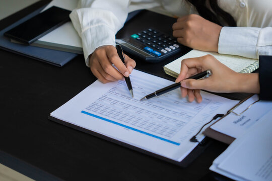 Asian businesswoman using pen pointing at document