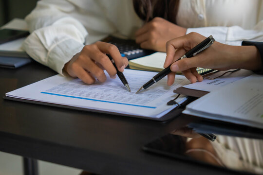 Asian businesswoman using pen pointing at document