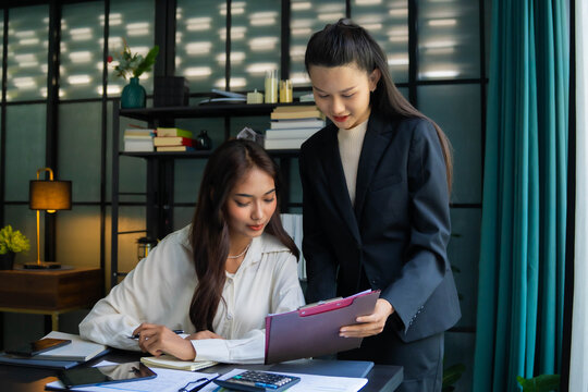 Asian boss businesswoman teaching intern work with document