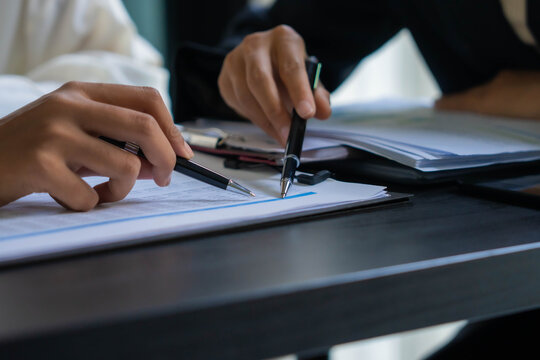 Asian businesswoman using pen pointing at document