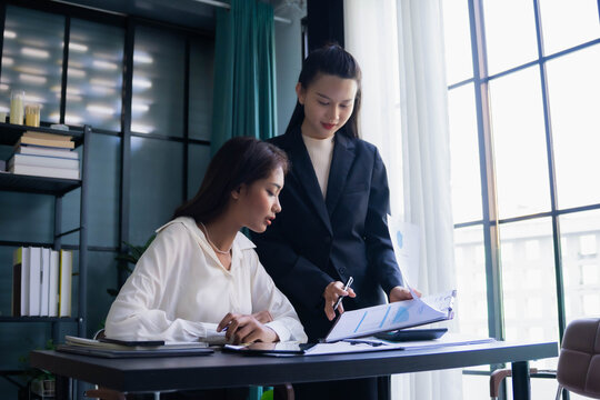 Asian boss businesswoman teaching intern work with document