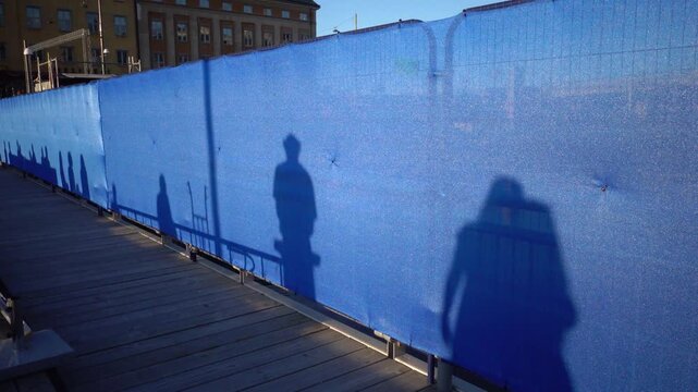 Stockholm, Sweden Shadows of people dancing at sunset projected onto a blue construction screen in the news redeveloped Slussen district. 