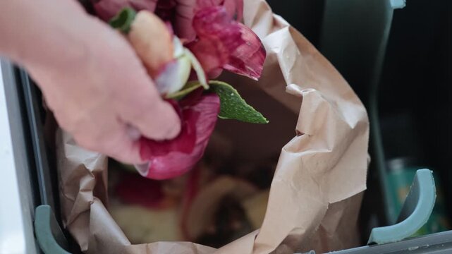 Stockholm, Sweden A person throws vegetable cuttings into a brown paper bag for recycling and composting in a residential kitchen. 
