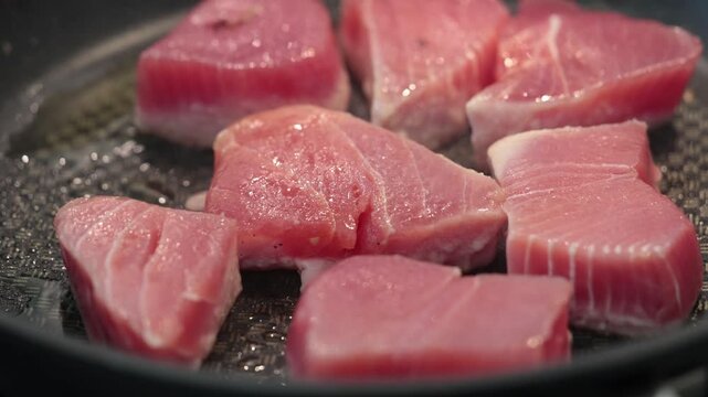 Stockholm, Sweden Raw tuna steaks frying n a frying pan. 