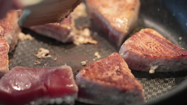 Stockholm, Sweden Raw tuna steaks frying n a frying pan. 